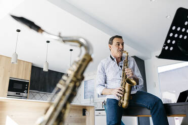 Saxophonist spielt Saxophon auf einem Tisch zu Hause - JRFF05323