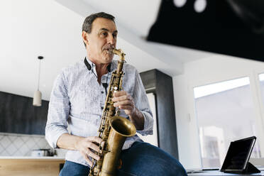 Musiker übt Saxophon am Tablet-PC zu Hause - JRFF05324