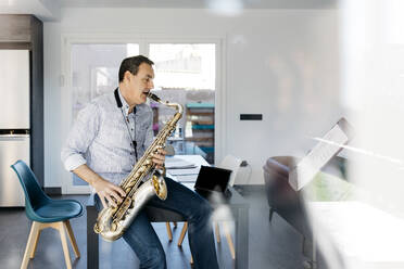 Saxophonist bläst Saxophon auf einem Tisch zu Hause - JRFF05329