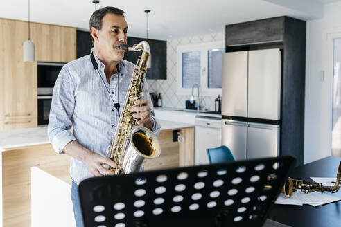 Saxophonist übt Saxophon stehend in der Küche zu Hause - JRFF05331