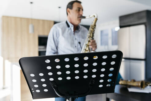 Saxophonist übt Saxophon vor einem Notenständer zu Hause - JRFF05333