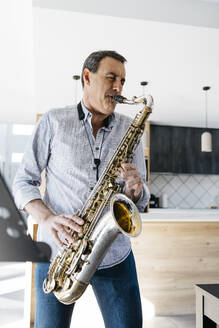 Saxophonist mit geschlossenen Augen spielt Saxophon zu Hause - JRFF05336