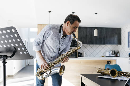 Musiker spielt Saxophon in der Küche am Tisch zu Hause - JRFF05337