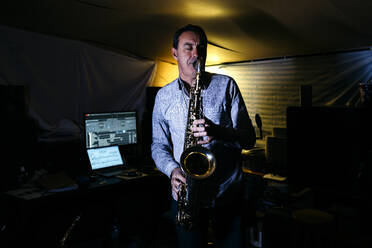 Musiker mit geschlossenen Augen übt Saxophon im Aufnahmestudio - JRFF05349
