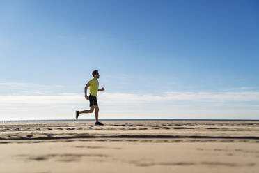 Sportler joggt am Strand unter bewölktem Himmel - DIGF17725