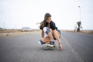 Junge Frau fährt Skateboard auf der Straße - FBAF01864