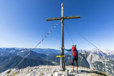 Wanderin beim Berühren des Gipfelkreuzes der Brunnensteinspitze - FOF13007