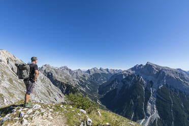 Männlicher Wanderer bewundert die Aussicht auf den Mittenwalder Hohenweg im Sommer - FOF13016