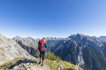 Female hiker admiring view of Mittenwalder Hohenweg in summer - FOF13019
