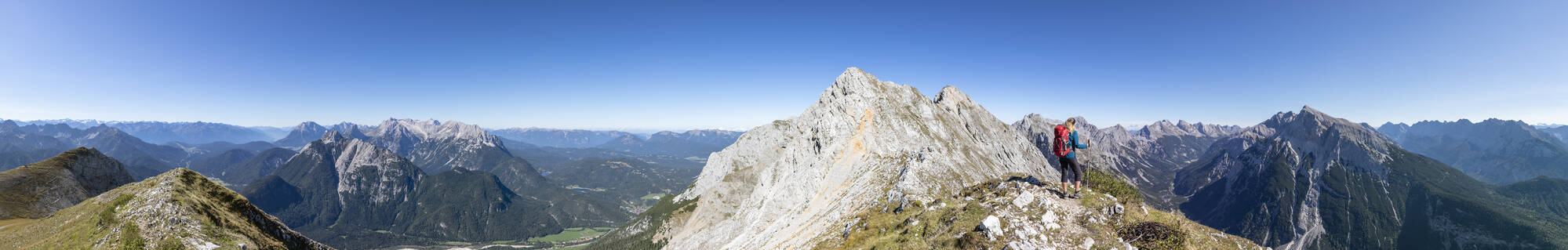 Panoramaansicht einer Wanderin, die die Aussicht auf den Mittenwalder Hohenweg und die umliegenden Berge im Sommer bewundert - FOF13020