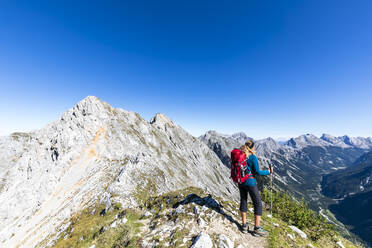 Female hiker admiring view of Mittenwalder Hohenweg in summer - FOF13022