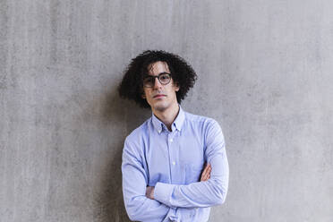 Man with arms crossed standing in front of gray wall - ASGF02178