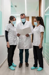 Doctor with nurses discussing medical report in maxillofacial clinic - DLTSF02833