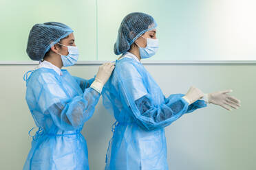 Krankenschwester hilft Arzt bei der OP-Kleidung im Krankenhaus - DLTSF02844