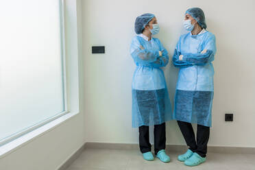 Krankenschwestern in OP-Kleidung stehen mit verschränkten Armen im Krankenhaus - DLTSF02845