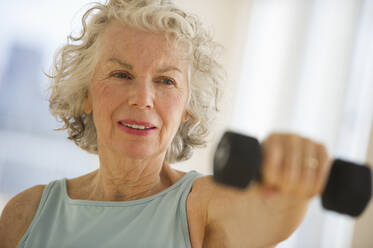 USA, New Jersey, Jersey City, Senior woman using hand weights at gym - TETF01473