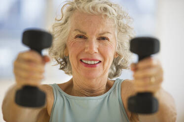 USA, New Jersey, Jersey City, Portrait of senior woman using hand weights at gym - TETF01474