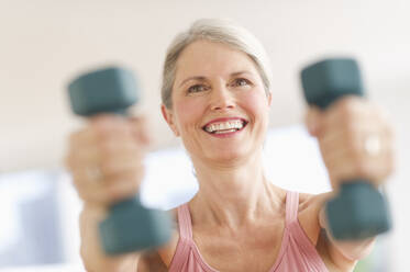 Portrait of senior woman exercising with dumbbells in gym - TETF01480