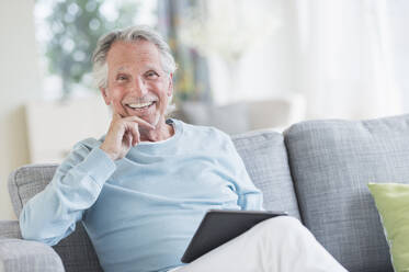 Senior man sitting on sofa with digital tablet - TETF01488