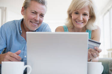 Porträt eines Paares, das einen Laptop benutzt, mit Blick auf eine Kreditkarte - TETF01494