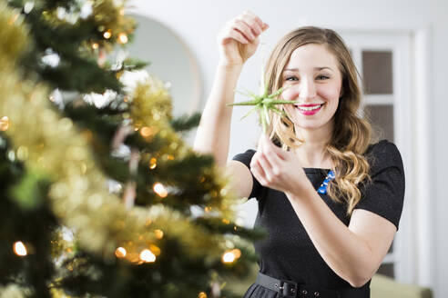 Junge Frau beim Schmücken des Weihnachtsbaums - TETF01524