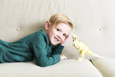Junge (2-3) auf Sofa liegend mit Spielzeugdinosaurier - TETF01527
