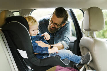 Man putting his son into car seat - TETF01553