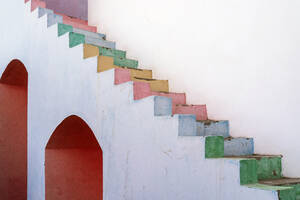White weathered house with painted wall and multicolored shabby steps located on street against cloudless sky in city of Egypt - ADSF34048
