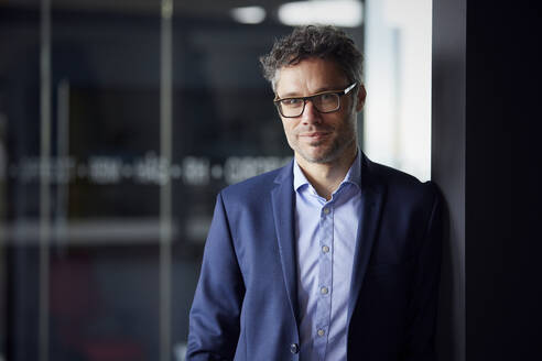 Geschäftsmann mit Brille im Büro stehend - RBF08639