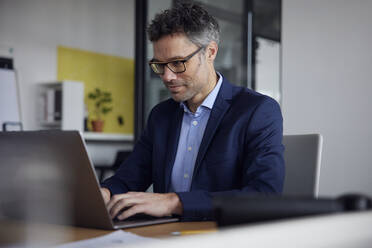 Geschäftsmann mit Brille und Laptop am Arbeitsplatz - RBF08647