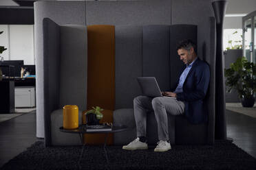 Geschäftsmann mit Laptop auf dem Sofa sitzend am Arbeitsplatz - RBF08659