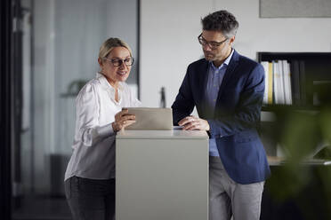 Geschäftskollege diskutiert über Tablet-PC am Schreibtisch im Büro - RBF08690