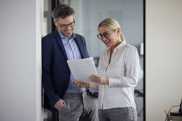 Glücklicher Geschäftskollege bei der Besprechung eines Dokuments im Büro - RBF08696