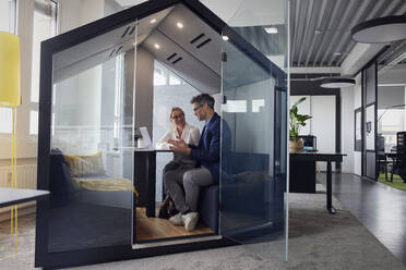 Businessman discussing with colleague in office cubicle - RBF08705