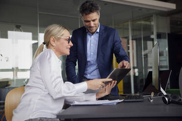 Geschäftsfrau teilt Tablet-PC mit Kollegen im Büro - RBF08716