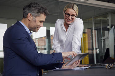 Businessman sharing tablet PC with colleague in office - RBF08717