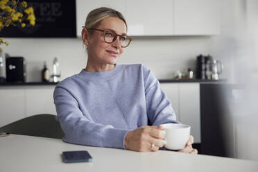 Geschäftsfrau mit Brille und Kaffeetasse an einem Tisch sitzend - RBF08743