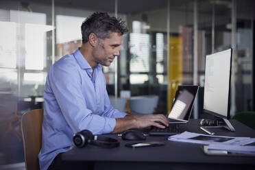 Geschäftsmann mit Computer bei der Arbeit im Büro - RBF08764