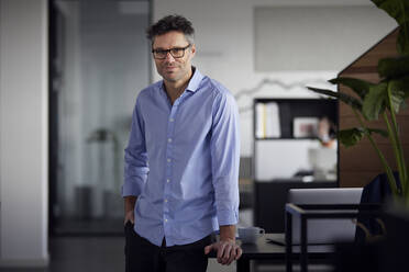 Geschäftsmann mit Brille, stehend mit Hand in der Tasche im Büro - RBF08770