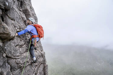 Mann mit Helm klettert auf felsigen Berg - ALRF01839