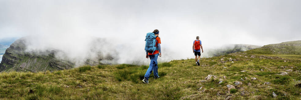 Bergsteiger mit Rucksack, die gemeinsam auf einer Wiese laufen - ALRF01850