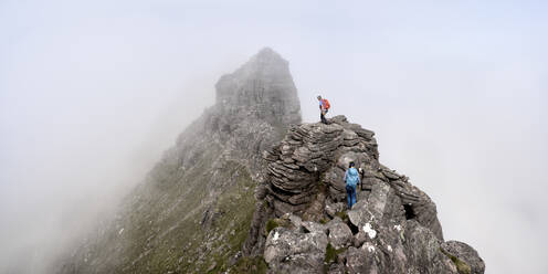 Mann und Frau wandern auf dem Gipfel eines felsigen Berges - ALRF01852