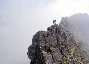Mann hilft Frau beim Besteigen eines felsigen Berges - ALRF01854