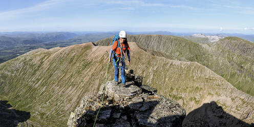 Frau mit Helm auf einem Berg an einem sonnigen Tag - ALRF01863