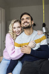 Lächelndes junges Paar sitzt zusammen zu Hause - PESF03578