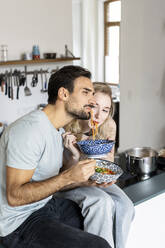 Freund und Freundin essen Nudeln in der Küche zu Hause - PESF03584