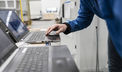 Hand eines Technikers, der einen Laptop in einer Fabrik benutzt - JCCMF05796