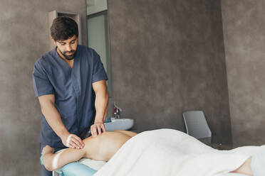 Physiotherapeutin bei der Massage einer Frau in einer medizinischen Klinik - MIMFF00802