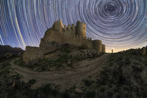 Entfernte Person mit glühenden Laterne stehend in der Nähe von mittelalterlichen Stein Burg gegen lange Belichtung Sternenhimmel in der Nacht auf dem Lande - ADSF34064