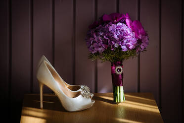 Creative bridal bouquet of pink flowers placed on wooden surface with light bridal shoes - ADSF34116